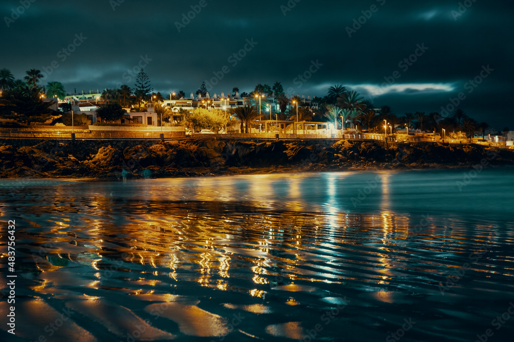cape with hotels and reflection in the sea at night