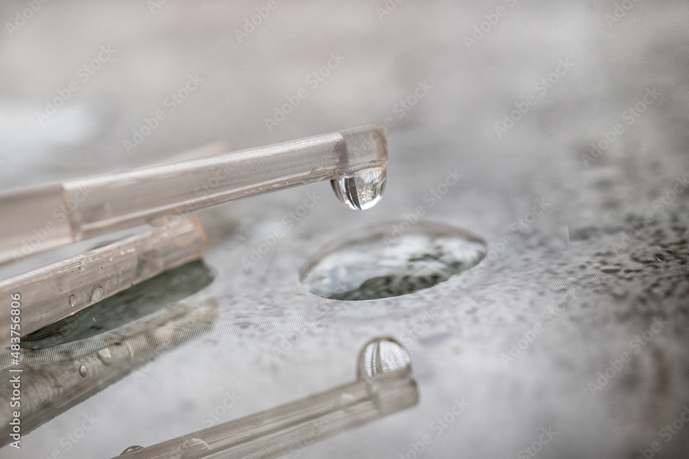 Close-up of water dripping from a plastic pipette on a bright background