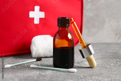 Obraz na płótnie Bottle with iodine, pipette, cotton swabs and first aid kit on grunge background