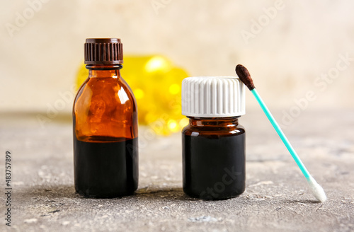 Bottles with iodine and cotton swab on grunge background