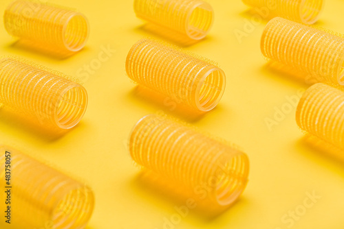 Set of hair curlers on yellow background, closeup