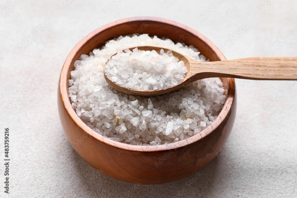 Wooden bowl with sea salt and spoon on light background, closeup Wooden bowl with sea salt and spoon on light background, closeup