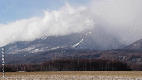 Timelapse of clouds over landscape under High Tatras rocky mountains in spring season, Slovakia. Green meadows in contrast with mountains covered with snow.