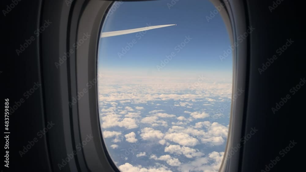 Aircraft porthole. Airplane flight, window view. Wing, blue sky and white clouds Aircraft porthole. Airplane flight, window view. Wing, blue sky and white clouds