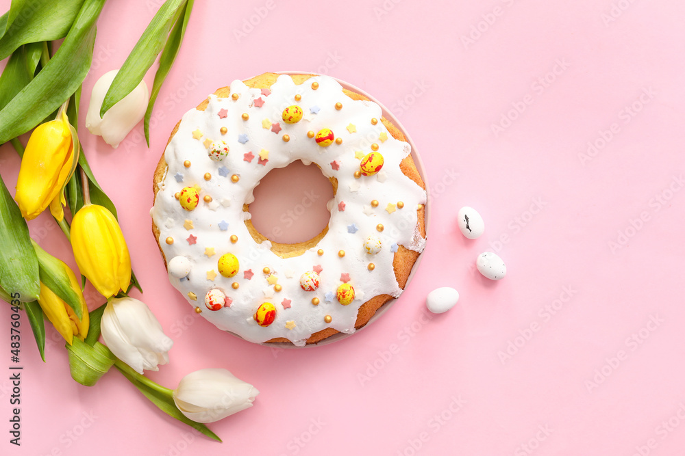 Plate with tasty Easter cake and tulip flowers on pink background Plate with tasty Easter cake and tulip flowers on pink background