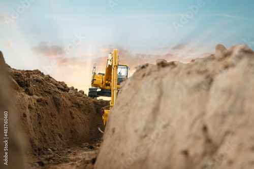 Selective focus ,Excavator with Bucket are digging canalize the soil in the construction site on the sunset background
