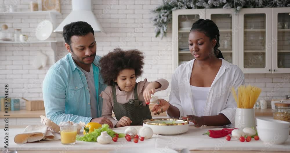 Parents help mixed race daughter cook according to recipe Parents help mixed race daughter cook according to recipe