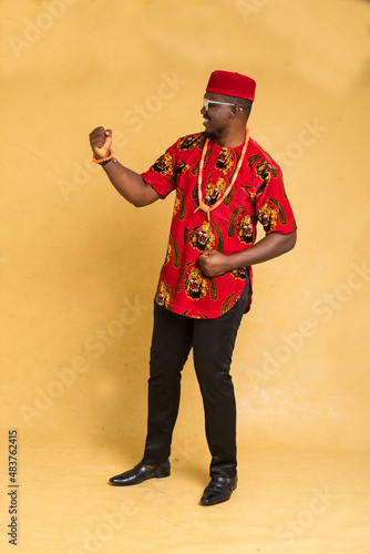 Igbo Traditionally Dressed Business Man Standing Fist Pump and Imaginary Product photo