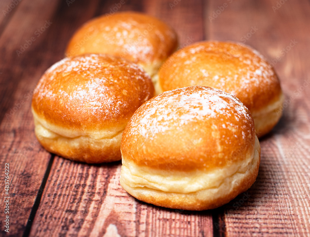 Decadent Delights: Austrian Krapfen and German Berliner, Oozing Creamy Goodness Inside. On wooden background. Selective focus.