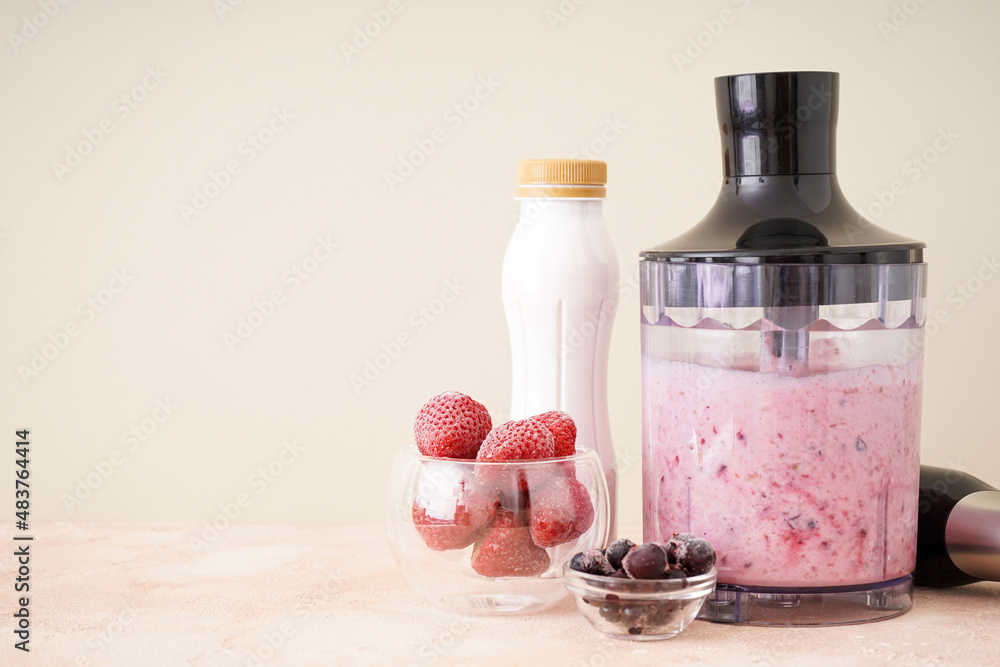 Hand blender for mixing organic fresh fruits smoothie on a color background, space for text, healthy food. Hand blender for mixing organic fresh fruits smoothie on a color background, space for text, healthy food.