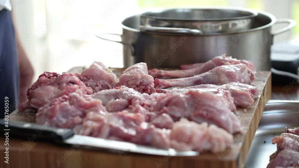 Chef adds spices to the butchered fresh rabbit meat lying on a cutting board on the table Chef adds spices to the butchered fresh rabbit meat lying on a cutting board on the table