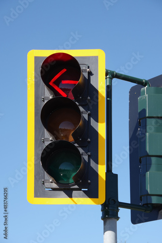 Yellow framed traffic signal showing a red stop arrow illuminated photo