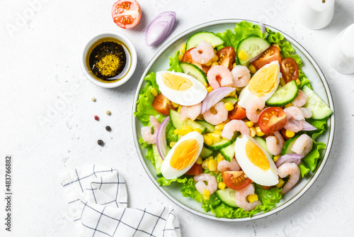 Summer colourful shrimp egg vegetable salad on plate on light background. Top view, copy space.