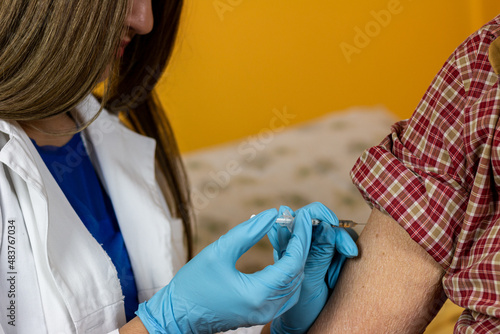 The doctor gives the vaccine to the pensioner at his home