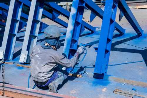 The painter uses a spray gun to paint a steel structure before transportation to the assembly yard.