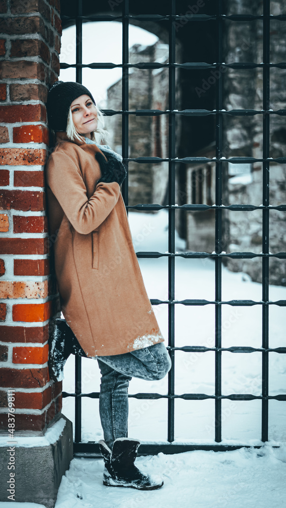 Fototapeta premium Zimowy portret kobiety na tle cegły. Portret na tle zamku.