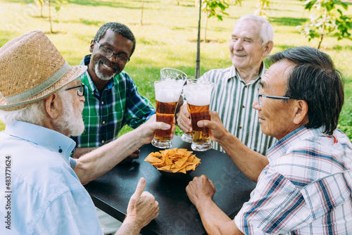 Group of senior friends drinking a beer at the park. Old multiethnic friends making activities outdoor. Concept about third age and lifestyle