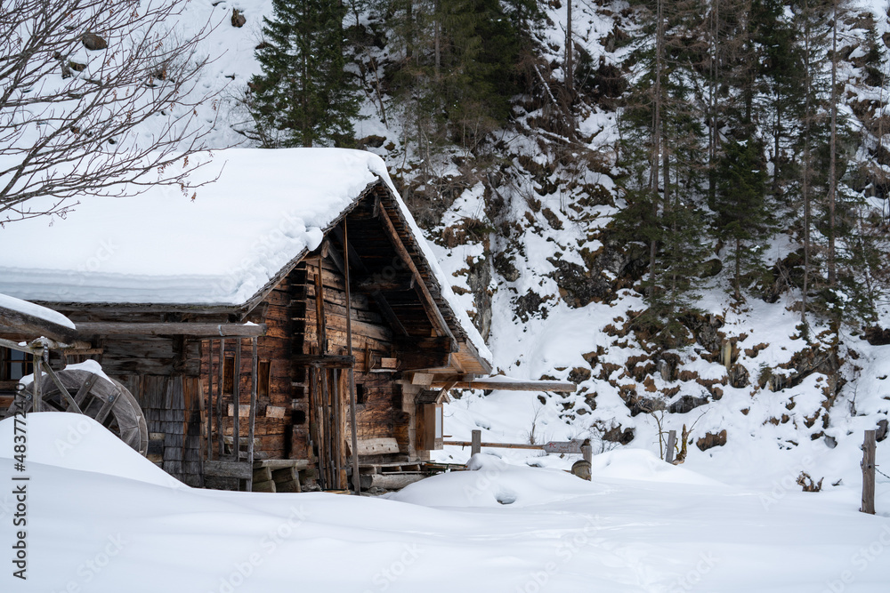 a traditional wood cabin at a farmland in the mountains in the snow capped hohe tauern national park at a winter day