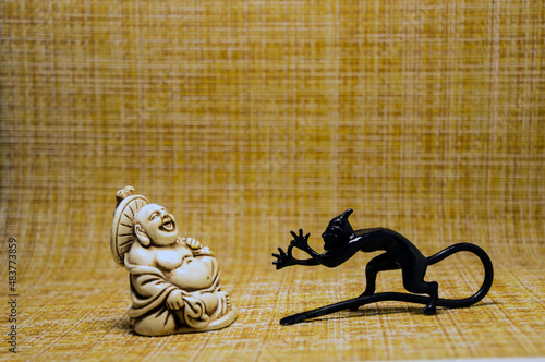 Fotografía Figurines of a little devil and a laughing monk who look at each other