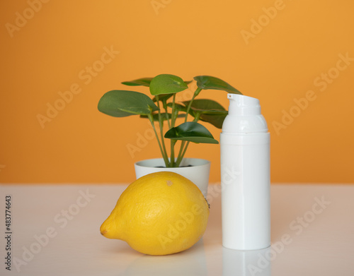Flacon blanc pour crème de beauté ou produit cosmétique sur fond jaune avec une plante verte et un citron - mock up pour texte ou design