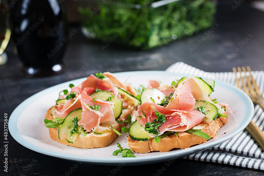 Breakfast or brunch. Open sandwich with prosciutto or jamon on white plate. Mediterranean appetizer. Breakfast or brunch. Open sandwich with prosciutto or jamon on white plate. Mediterranean appetizer.