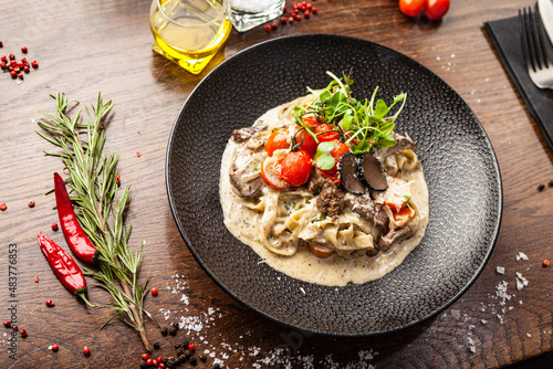 Black Angus beef tagliatelle pasta with fresh black truffles and parmegano. Delicious healthy traditional food closeup served for lunch in modern gourmet cuisine restaurant