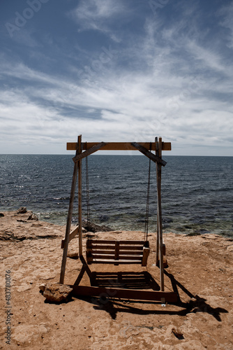 Swing on the shore of the blue sea on the yellow sand © Елена Дроздова