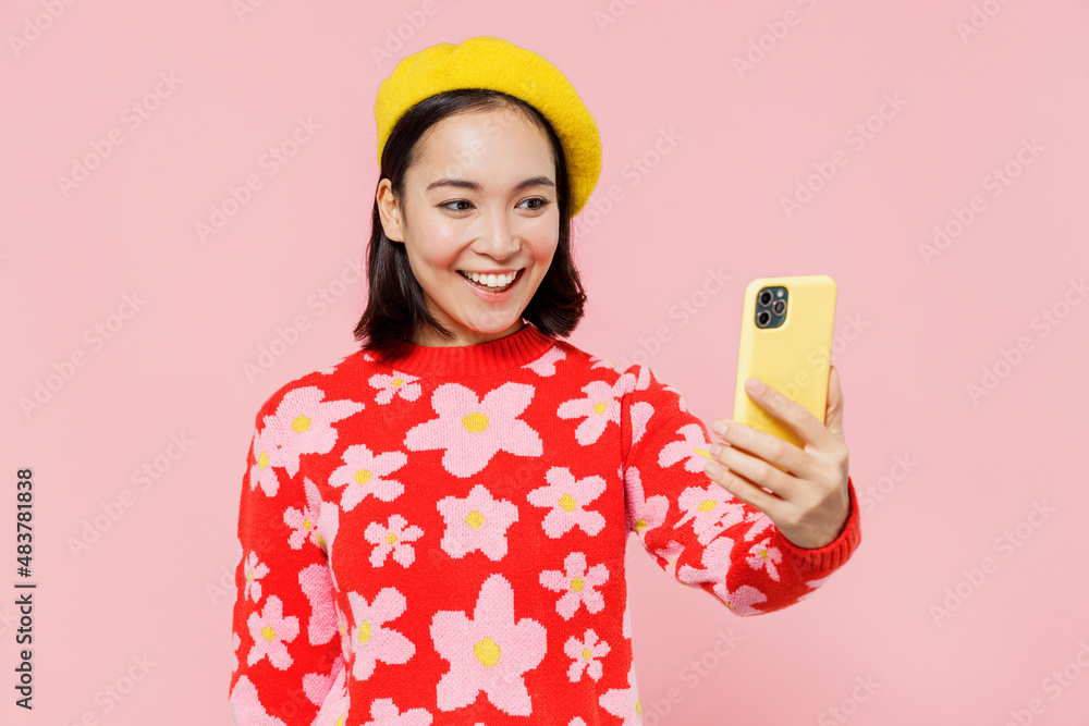 Smiling happy woman of Asian ethnicity 20s wear red knitted sweater beret doing selfie shot on mobile cell phone post photo on social network isolated on plain pastel pink background studio portrait Smiling happy woman of Asian ethnicity 20s wear red knitted sweater beret doing selfie shot on mobile cell phone post photo on social network isolated on plain pastel pink background studio portrait