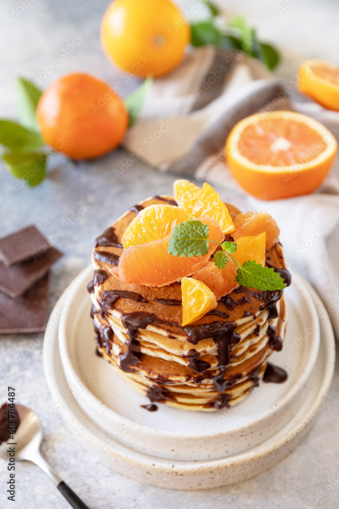 Celebrating Pancake day, healthy breakfast. Delicious homemade american bananas pancakes with chocolate and red orange on grey stone background. Celebrating Pancake day, healthy breakfast. Delicious homemade american bananas pancakes with chocolate and red orange on grey stone background.
