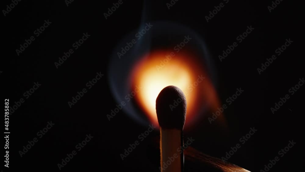 Person igniting matchstick against black background Person igniting matchstick against black background