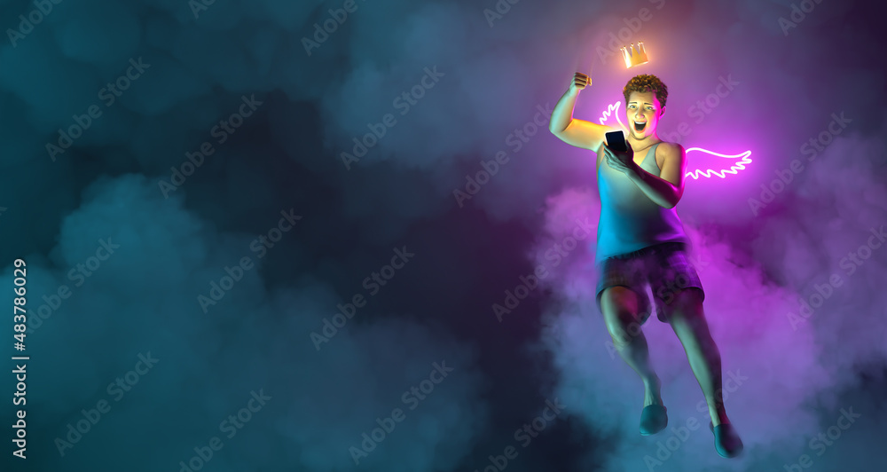 A flying excited and impressed man in casual clothes holding mobile phone. Glowing wings and crown. Night sky neon illumination