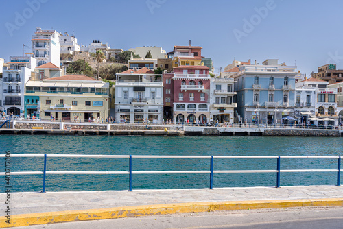 Agios Nikolaos, Crete, Greece - September 30, 2021 View at the calm sea in small port harbor and colorful houses, hotels and shops