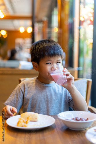 Asian kid have a glass of milk for breakfast. Concept of healthy breakfast