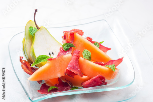 melon cantaloupe and pear with proscutto and mint leaves