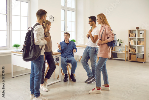 Happy multiethnic young people with backpacks talk discuss ideas in college or school. Smiling diverse multiracial groupmates or students speak chat at break in university. Education time concept.
