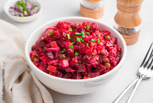 Traditional Russian salad vinaigrette with beets, potatoes, carrots and sauerkraut on a gray one.