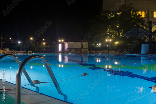 Swimming pool at night, illuminated turquoise water