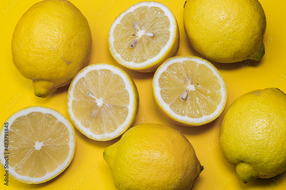 joyful background of halved lemons and whole lemons on a yellow paper background