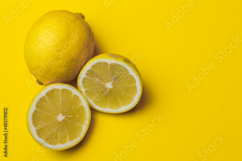 two half lemons and one whole lemon on a yellow paper background with plenty of room for text