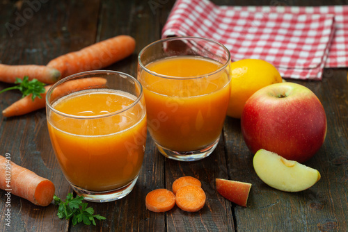 Natural organic fresh juice made of carrots and apples on wooden table. Healthy carrot, apple and lemon smoothie.