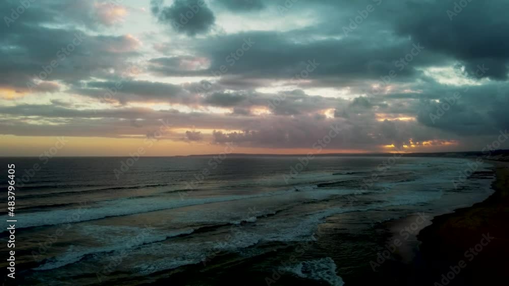 Spooky storming scene over the sea with storm clouds overhead sun peaking through the clouds on the horizon Spooky storming scene over the sea with storm clouds overhead sun peaking through the clouds on the horizon