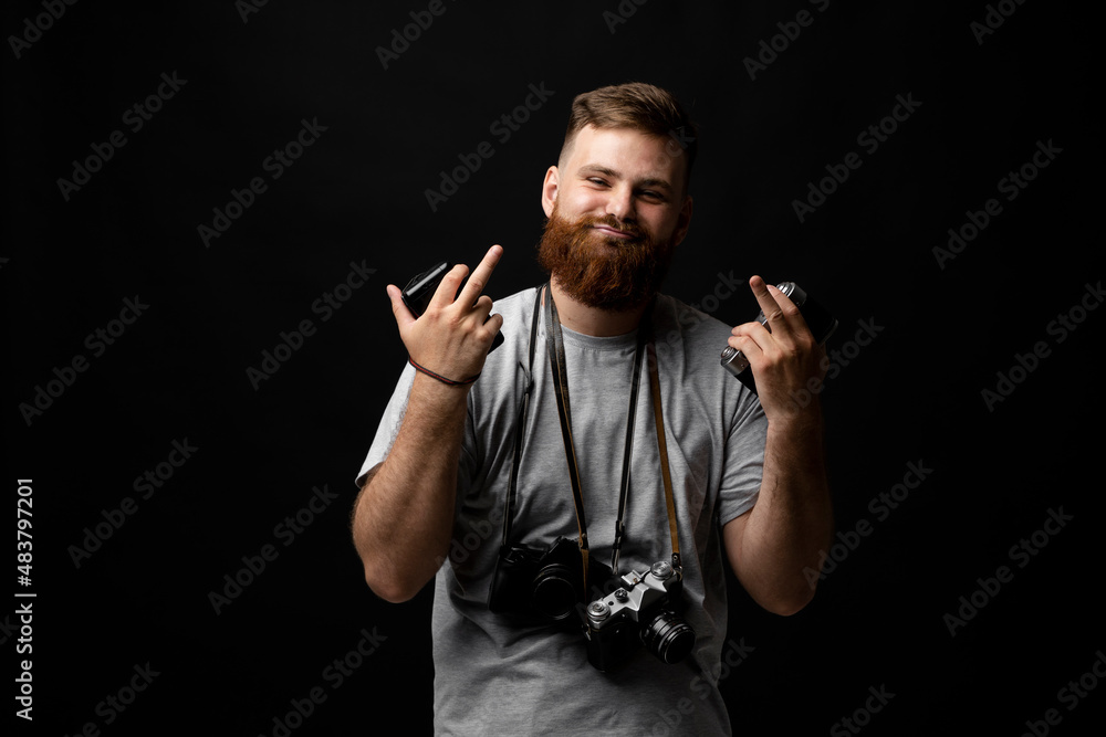 Professional handsome bearded male photographer with bunch of vintage photo cameras show a middle finger with both hands in photo studio. Professional handsome bearded male photographer with bunch of vintage photo cameras show a middle finger with both hands in photo studio.