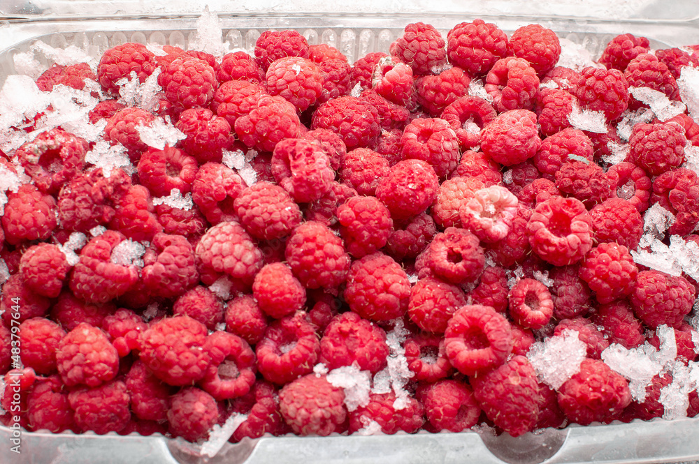 Deep frozen raspberries in a plastic container. Top view. Preservation of vitamin in berries, healthy nutrition in winter Deep frozen raspberries in a plastic container. Top view. Preservation of vitamin in berries, healthy nutrition in winter