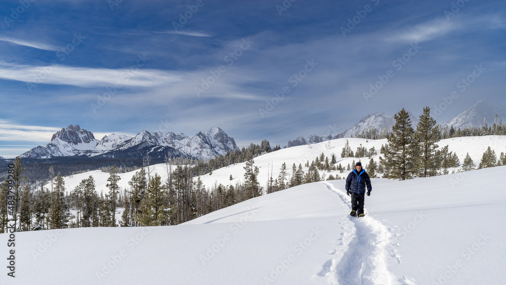 Man snowshoes in the Idaho wilderness following a trail