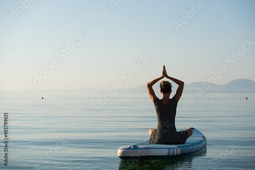 Mindful young woman sitting in lotus position with her palms joined above her head