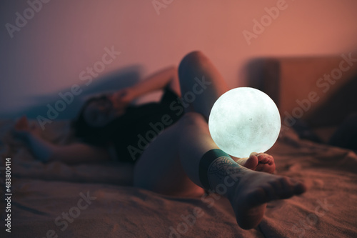 Sexy portrait of a woman lying in bed. Focus on the legs. Warm ambient light.
