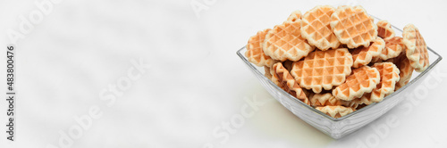 Belgian waffles in a glass bowl. holiday cookies on a white background. fresh baking concept. sweet desserts on a light texture
