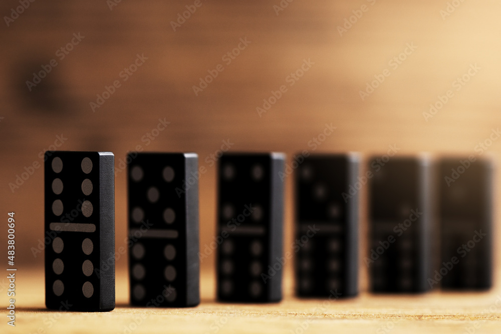 Chain of black plastic domino tiles with white symbols standing one after another. Chain of black plastic domino tiles with white symbols standing one after another.