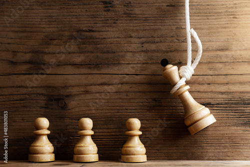 Billede på lærred Wooden chess queen hanging on a white rope with pawns standing below