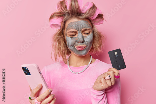 Carta da parati Upset woman lacking on money looks at credit card uses mobile phone application